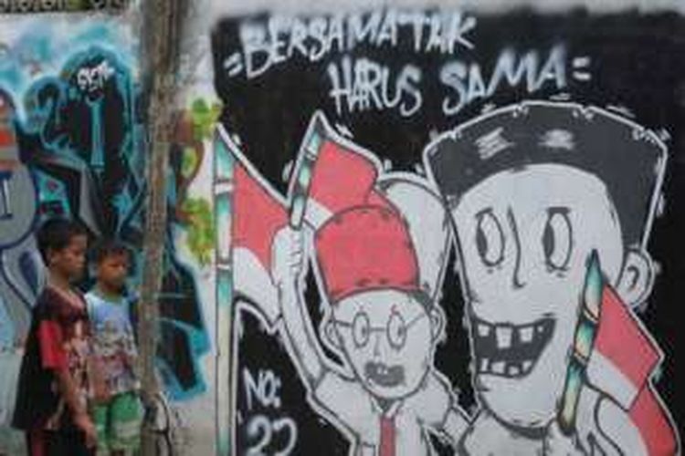 Warga melintas di dekat mural yang menyuarakan semangat kebersamaan dalam perbedaan di Jalan Kramat Jaya Baru, Jakarta Pusat, Senin (31/3/2014). Mural tersebut menjadi media bagi warga sekitar untuk menjaga kerukunan dan kedamaian di tengah perbedaan suku, agama, warna kulit, dan jender.