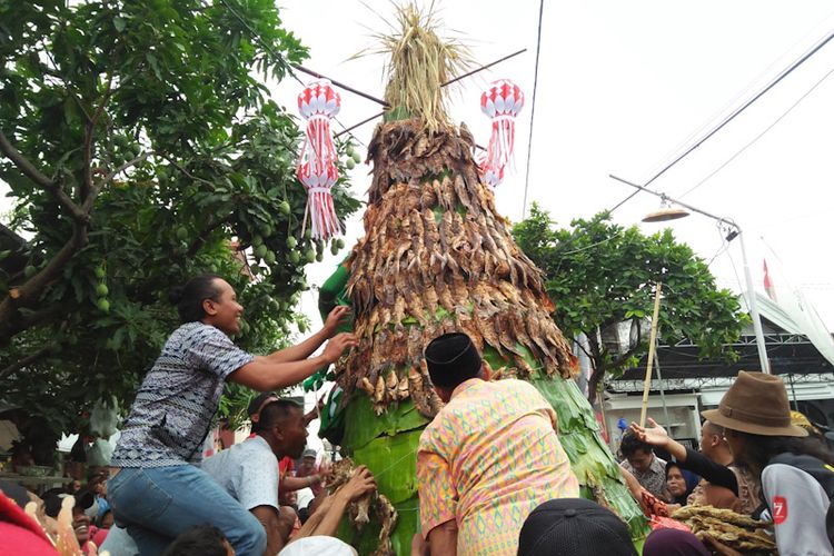 Warga saat berebut gunungan ikan setinggi 4 meter dalam acara sedekah bumi Desa Pandanan, Kecamatan Duduksampeyan, Gresik, Jawa Timur, Jumat (9/9/2022) sore WIB.