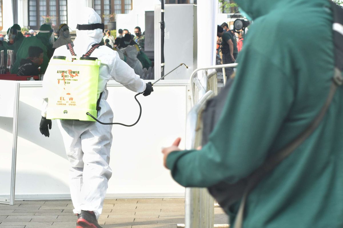 Petugas berpakaian APD tengah menyemprotkan disinfektan di pagar pembatas jalur keluar tempat tes massal yang digelar Badan Intelijen Negara (BIN) di Gedung Sate, Jalan Diponegoro, Kota Bandung, Jumat (26/6/2020). BIN membawa 40 orang tenaga medis dan dokter serta dua mobil laboratorium covid-19 dalam tes massal selama tiga hari di Bandung.