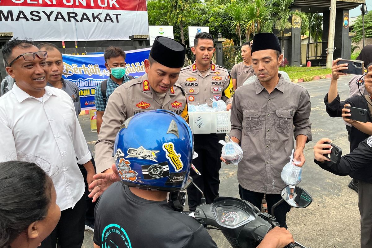 Pemotor melintas dan menerima takjil di depan halaman Mapolres Probolinggo, Jawa Timur. 