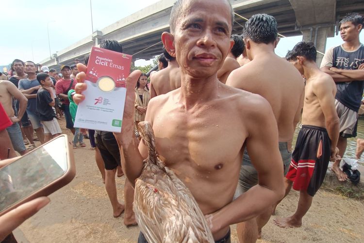 Muchtar (45), warga RT 003/RW 04 Cipinang Melayu yang berhasil mendapatkan satu gram emas murni usai menangkap bebek berpita merah putih di Kalimalang, Cipinang Melayu, Makasar, Jakarta Timur, Minggu (20/8/2023).