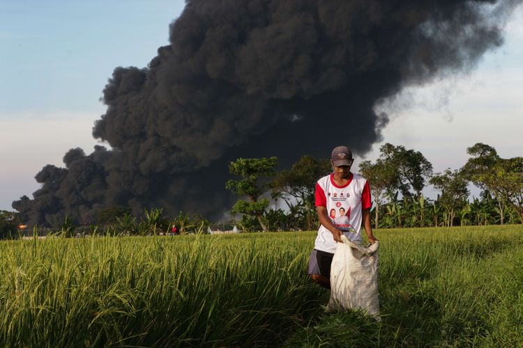 Asap membubung tinggi akibat kebakaran kilang minyak milik Pertamina RU VI di Balongan, Indramayu, Jawa Barat, Senin (29/3/2021).  Tangki di kilang minyak milik Pertamina ini terbakar pada Senin, pukul 00.45 WIB.