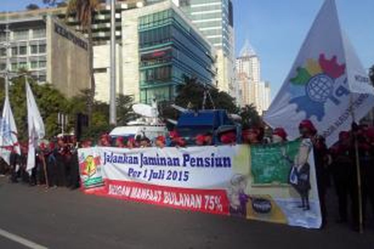 Para buruh menggelar spanduk dalam perayaan Hari Buruh di Bundaran HI, Jumat (1/5/2015).