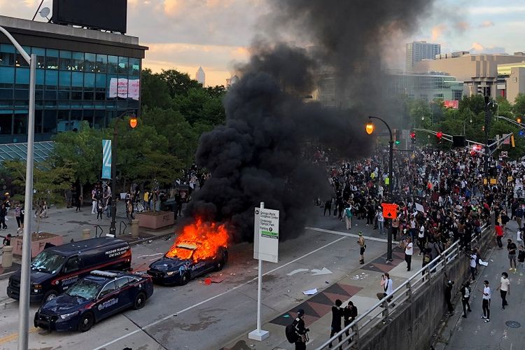 Sebuah mobil Polisi di Atlanta dibakar massa ketika demonstran memprotes kematian pria Afrika-Amerika George Floyd, dekat CNN Center di Atlanta, Georgia, AS, 29 Mei 2020. 