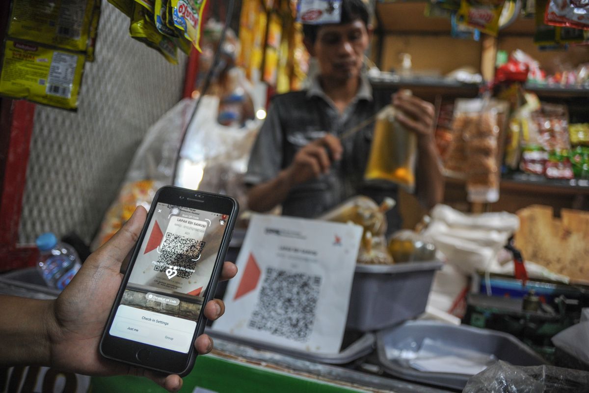 Warga menunjukkan aplikasi Peduli Lindungi saat membeli minyak curah di Pasar Kosambi, Bandung, Jawa Barat, Senin (27/6/2022). Pemerintah akan menerapkan aturan baru terkait pembelian dan penjualan minyak goreng curah dengan menggunakan aplikasi Peduli Lindungi atau menunjukkan nomor induk kependudukan pada KTP yang akan diberlakukan pada 11 Juli mendatang. ANTARA FOTO/Raisan Al Farisi/aww.