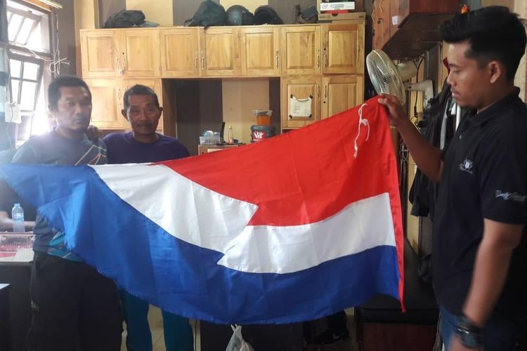Poisi menurunkan paksa dan menyita umbul-umbul yang mirip bendera Belanda, Minggu (18/8/2019).