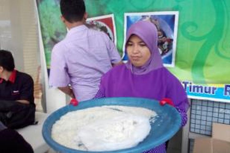 Dewi Septiani membawa tampah berisi beras yang diduga terbuat dari plastik di Mutiara Gading Timur, Selasa (19/5/2015). 
