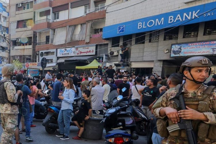 Pasukan keamanan Lebanon dikerahkan ketika orang-orang berkumpul di luar cabang Bank Blom di lingkungan Tariq al-Jdideh di ibu kota Beirut pada 16 September 2022, untuk menyatakan dukungan mereka kepada seorang deposan, yang menyerbu bank menuntut untuk menarik tabungannya yang dibekukan.