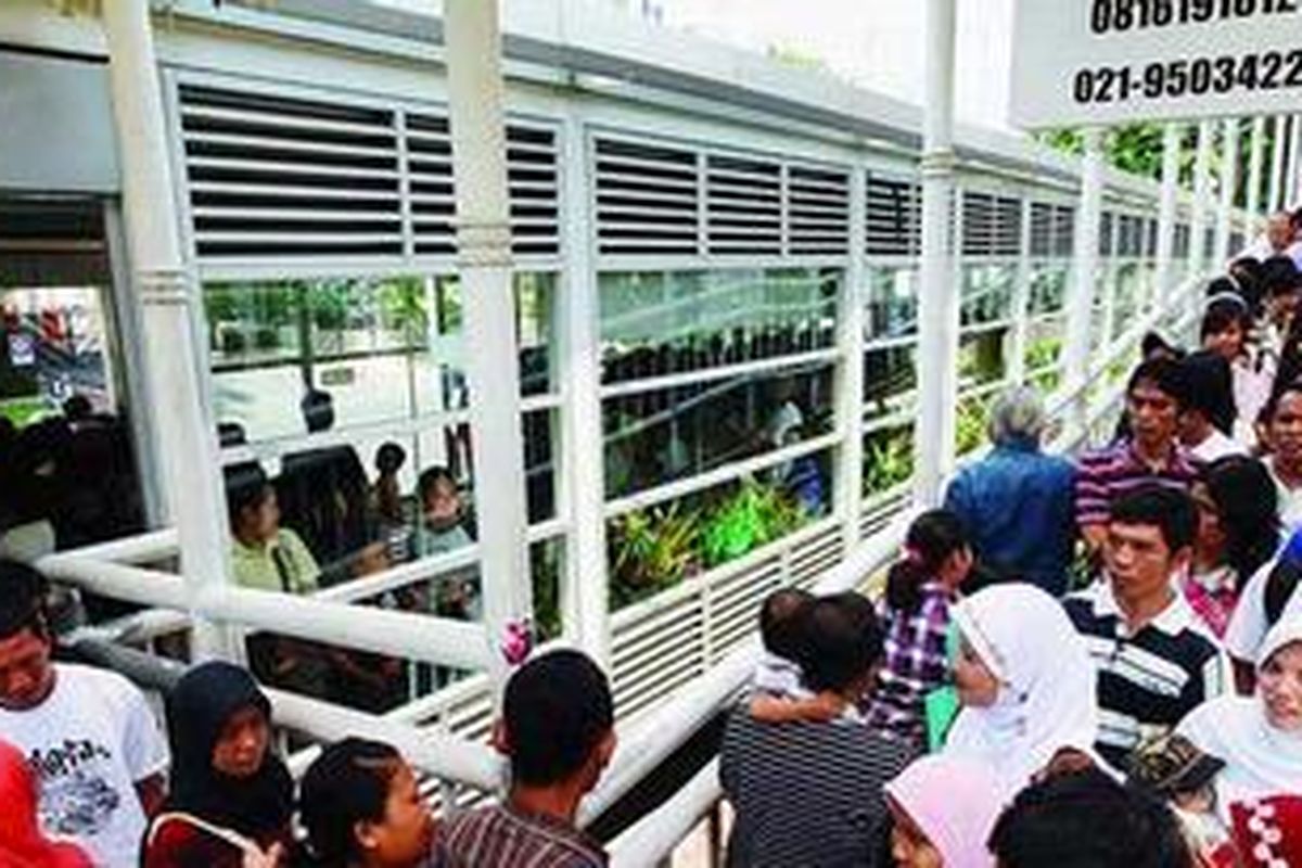 Warga yang hendak menumpang bus transjakarta, rela antri berdesak-desakkan.