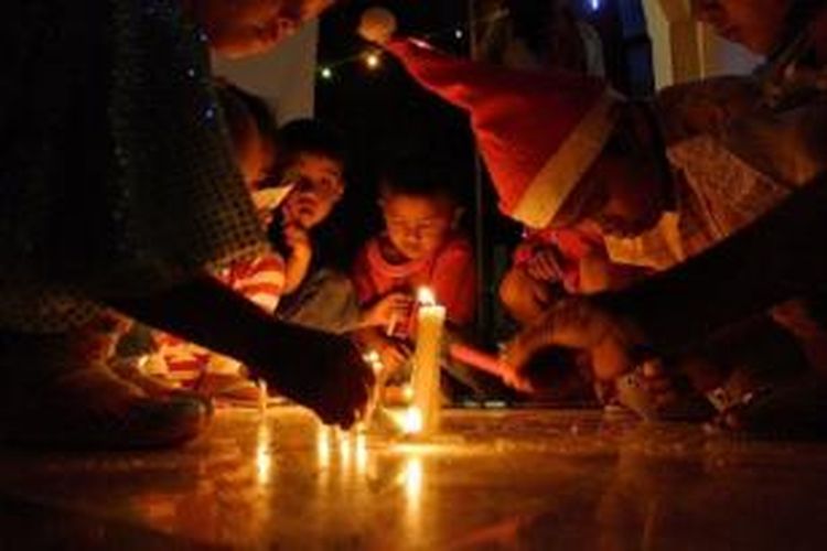 Anak-anak pengungsi bermain lilin dalam acara perayaan Natal di Gereja Batak Karo Protestan Simpang VI Kabanjahe, Karo, Sumut, Jumat (19/12). Para pengungsi percaya bahwa bencana Gunung Sinabung akan membawa kebaikan bagi umat.