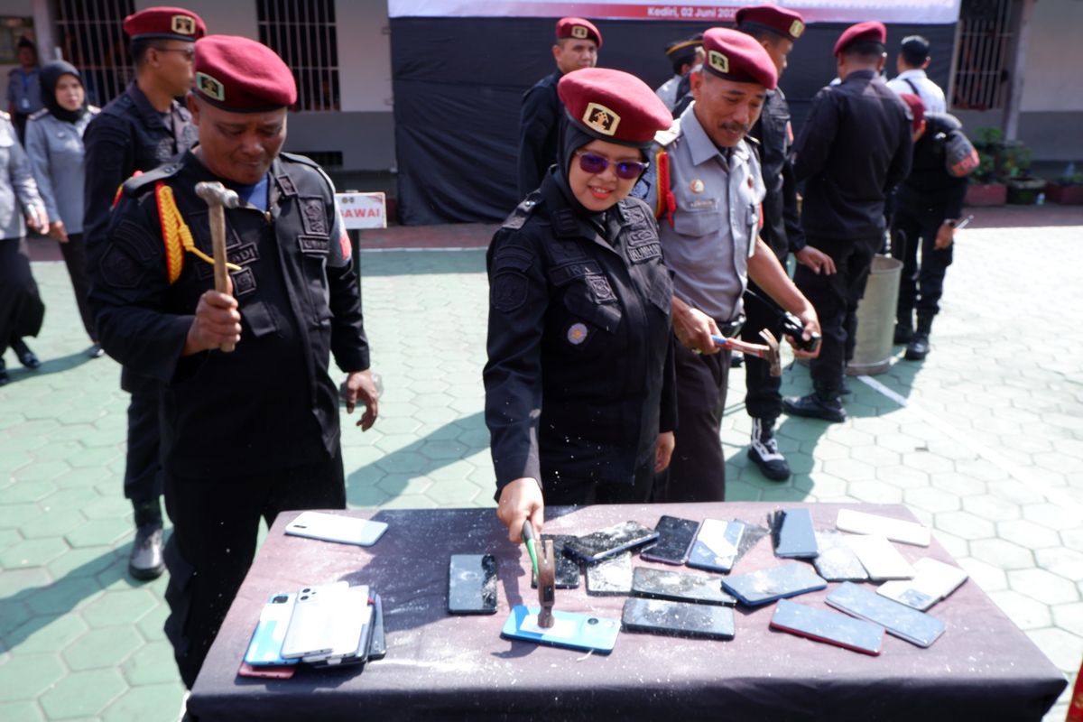 Petugas Lapas Kelas II A Kediri, Jawa Timur, menghancurkan ponsel sitaan dari penghuni lapas sebagai simbol perang terhadap ponsel dan narkoba di lapas Kediri, Senin (2/6/2025).