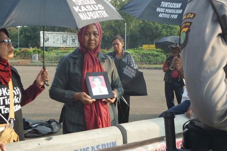 Maria Sanu, ibu korban kerusuhan Mei 1998, sedang berdiri sambil memegang foto anaknya yang menjadi korban kerusuhan, dalam Aksi Kamisan ke 443 di depan Istana Negara, Kamis (19/5/2016).