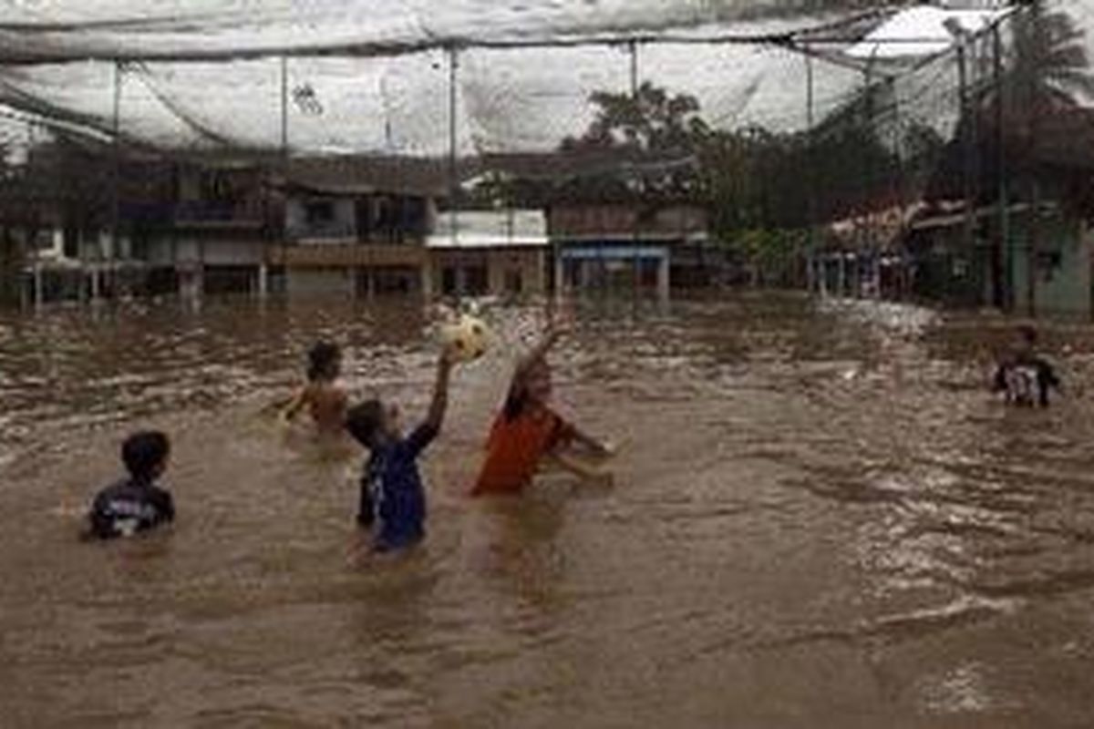 Anak-anak bermain bola di lapangan futsal yang terendam luapan Kali Ciliwung di RT 02 RW 07 Kelurahan Rawajati, Kecamatan Pancoran, Jakarta Selatan, Selasa (15/1/2013). Luapan Kali Ciliwung, Rabu (16/1/2013), kembali menggenangi ratusan rumah di bantaran Kali Ciliwung di Jakarta.