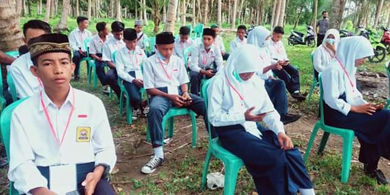 Puluhan siswa MTs Baiturrahman di Desa Salimuli, Kecamatan Galela Utara, Kabupaten Halmhera Utara, Maluku Utara, yang melaksanakan ujian madrasah (UM) di pinggir pantai, Sabtu (27/3/2021). Foto: Facebook (Jusnidar)