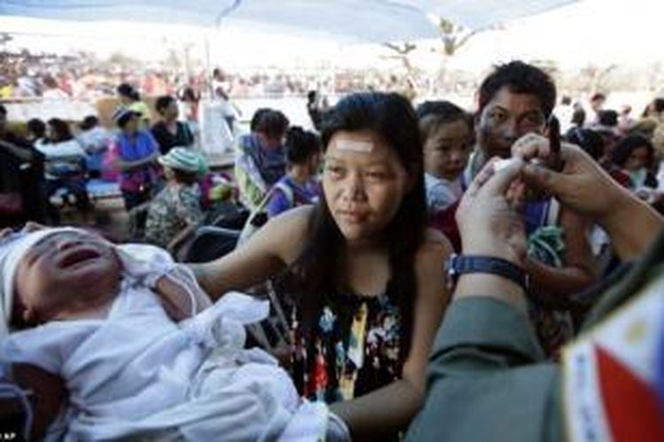 Bayi berusia satu hari, Ian Daniel Honrado, diserahkan ibunya Roselle ke tangan seorang tentara , sementara dia menyusul naik ke atas sebuah pesawat angkut militer di bandara Tacloban.
