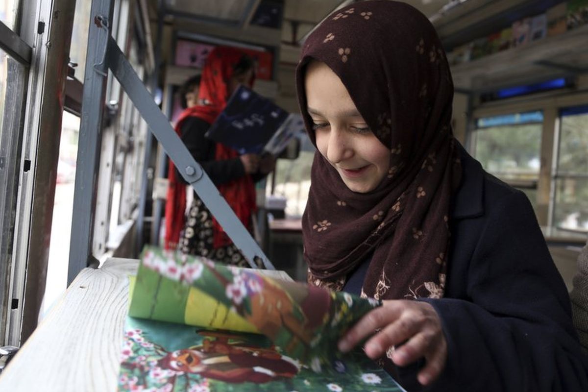 Seorang anak Afghanistan membaca buku di dalam perpustakaan bus, Charmaghz, di Kabul.