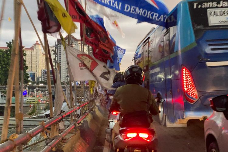 Sejumlah alat peraga kampanye (APK) berupa bendera partai politik terpasang ke pipa pagar jembatan di flyover Grogol, Jakarta Barat, Senin (5/2/2024).