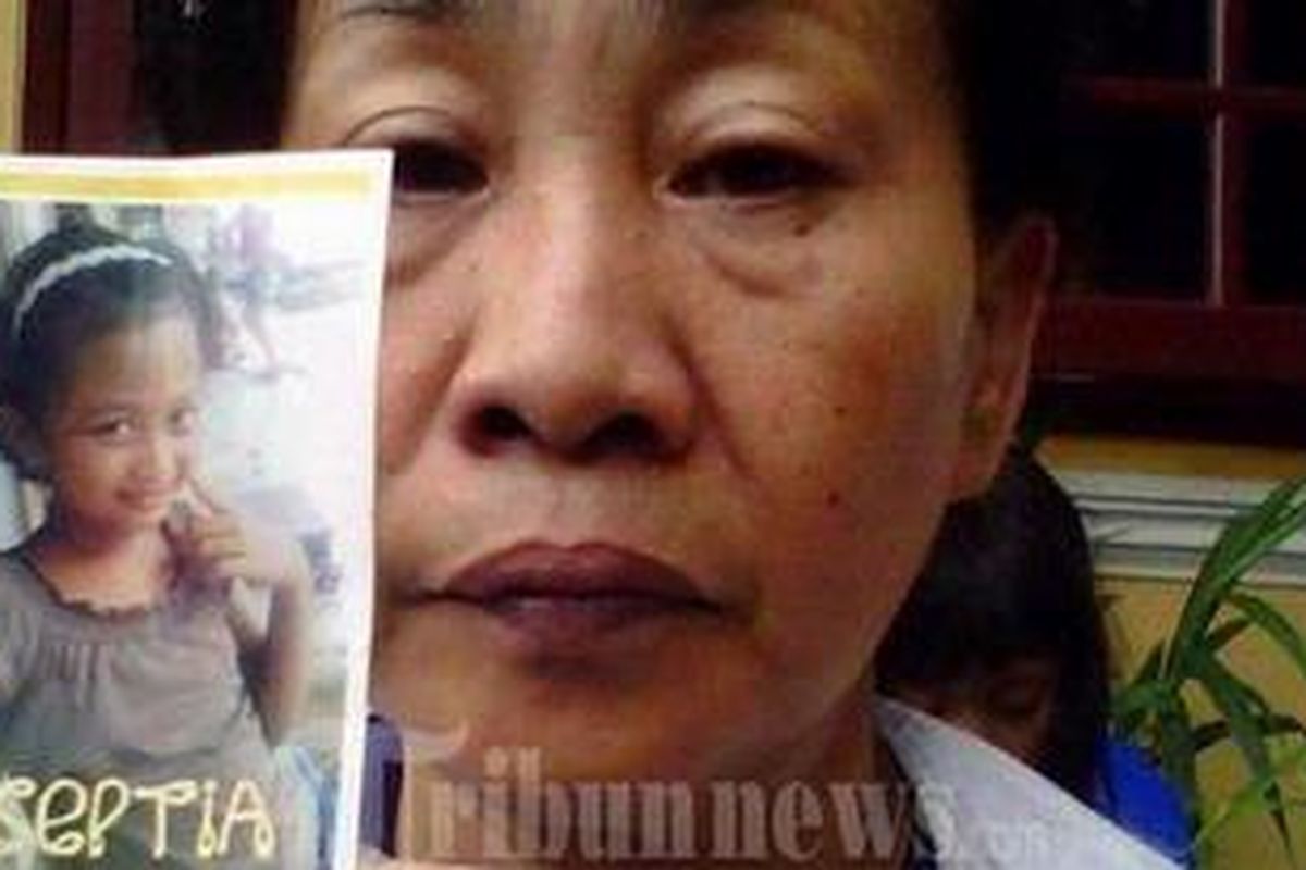 Juju (51) memegangi foto cucunya, Septia Riski, yang hanyut usai titian ambruk ke sungai Cihideung, Minggu (19/02/2012)