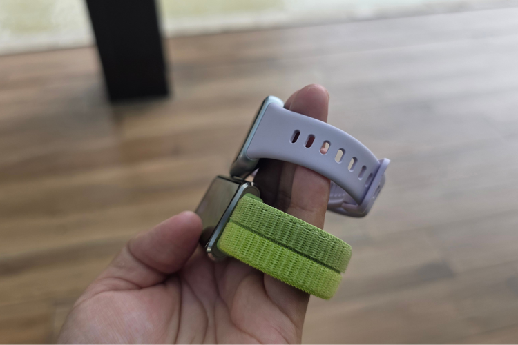 Perbandingan strap kedua perangkat. Varian Pro dengan strap berwarna hijau (Green) dan varian reguler dengan strap berwarna ungu (Purple).