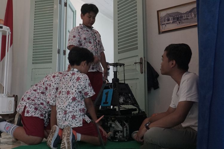 Siswa SD Kristen Satya Wacana mendengarkan penjelasan tentang robot yang dipamerkan.