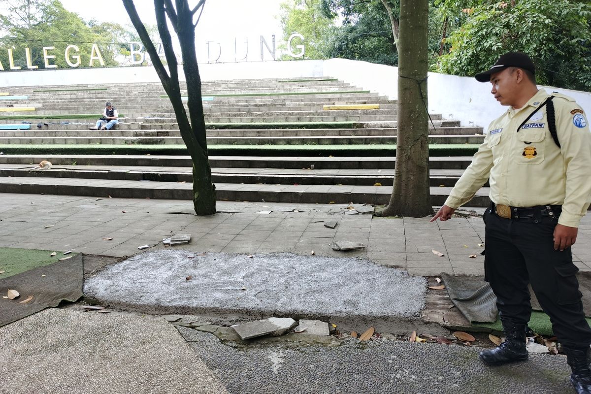 Petugas keamanan menunjukkan lokasi area Taman Tegalega, Kota Bandung, Jawa Barat yang sudah diperbaiki setelah rusak akibat aktivitas pencarian koin digital pada pekan lalu, Senin (13/1/2025).