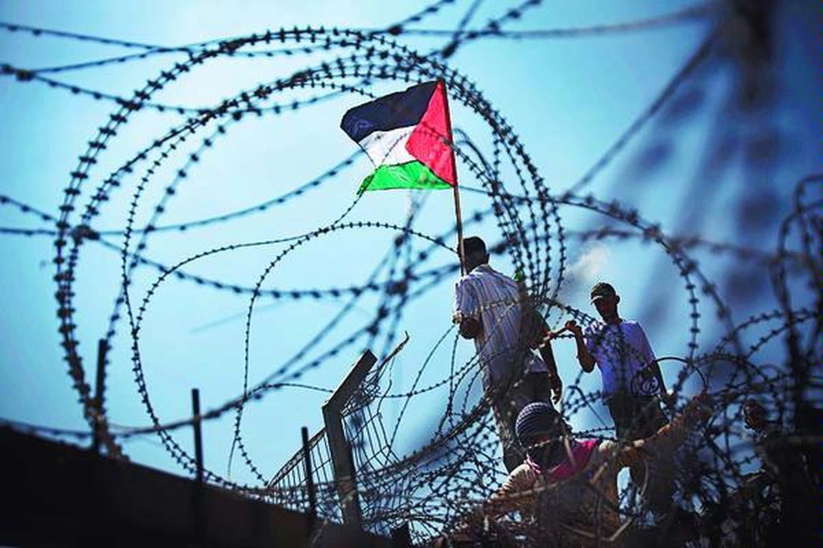 Aktivis Palestina berkumpul di dekat pagar pembatas yang dipasang Israel, Jumat (21/8), di desa Bilin, Tepi Barat, Palestina. Kota Bilin berada di dekat Ramallah, markas pemerintahan Fatah.