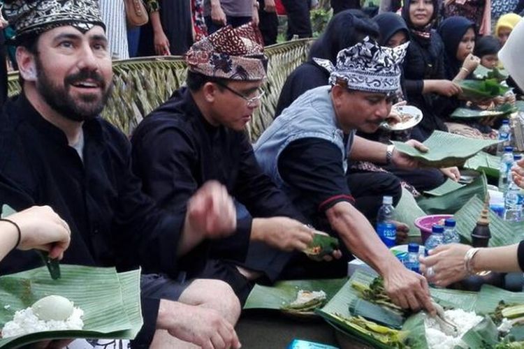 Warga dan wisatawan menikmati kuliner khas suku Osing, Pecel Pithik yang dihidangkan dalam selametan masyarakat Desa Kemiren, Banyuwangi.