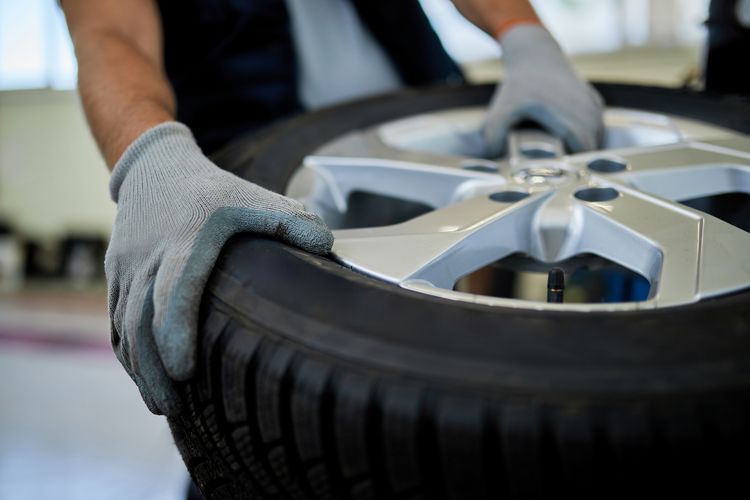 Teknisi bengkel melakukan perbaikan ban mobil