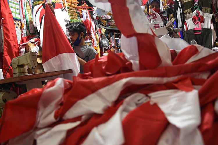 Pekerja menjahit bendera merah putih di kiosnya di kawasan Pasar Senen, Jakarta, Selasa (4/8/2020). Menjelang peringatan HUT ke-75 Kemerdekaan Republik Indonesia, sejumlah pedagang mengaku penjualan pernak-pernik bendera merah putih mengalami penurunan 50 persen dibanding tahun lalu atau dari produksi 80 bendera per hari menjadi 40 bendera per hari akibat pandemi Covid-19.