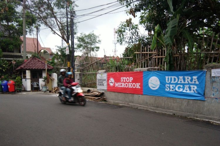 Salah seorang pengendara saat melintasi spanduk imbauan larangan merokok di Komplek Pandanwangi RT 09, Kelurahan Cijawura, Kecamatan Buahbatu, Bandung, Selasa (26/9/2017).