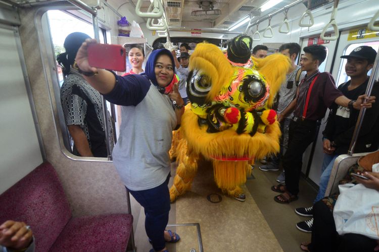 Seorang penumpang kereta sedang berswafoto bersama barongsai di Stasiun Bogor, Jumat (16/2/2018). Memeriahkan Imlek 2018, PT PT Kereta Commuter Indonesia (KCI) menghibur para penumpang di Stasiun Bogor dengan suguhan pertunjukan barongsai, pembagian fortune cookies, dan angpao.