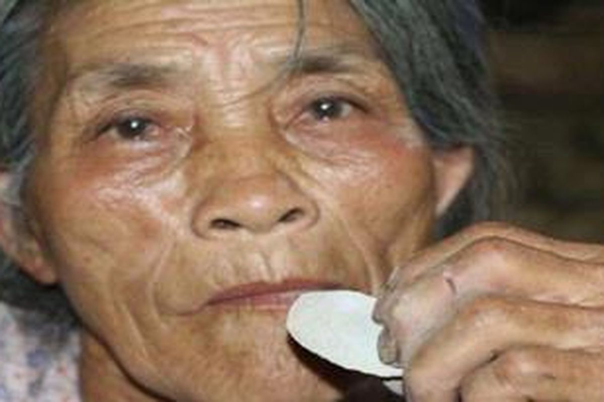 Seorang perempuan asal Vietnam sedang mengunyah kue yang terbuat dari tanah liat.