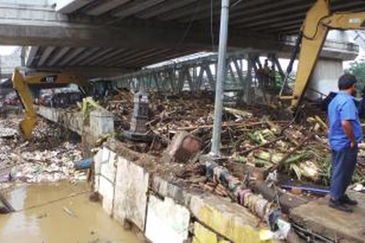 Petugas melakukan pembersihan sampah yang mencapai ratusan ton dengan alat berat di Kolong Jembatan Kalibata, Rawajati, Jaksel. Jumat (31/1/2014).