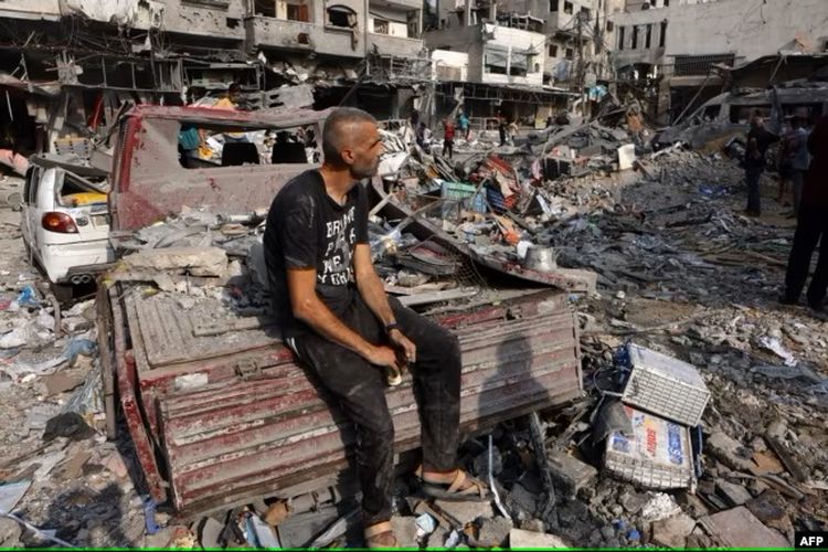 Seorang pria duduk terpekur di tengah kehancuran menyusul serangan Israel di kamp Al Shatee di Kota Gaza pada 28 Oktober 2023.