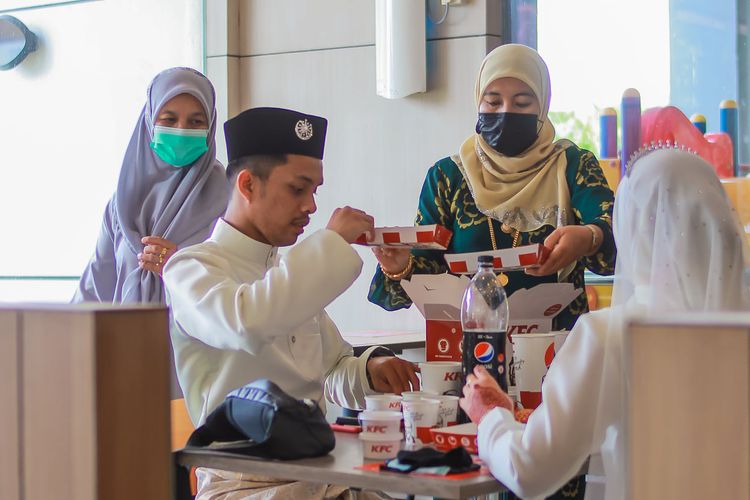 Sepasang pengantin baru di Teluk Intan, Perak, Malaysia, merayakan makan-makan setelah ijab kabul di KFC terdekat karena adanya pembatasan sosial.