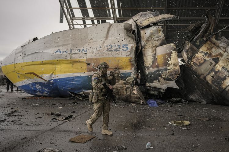 Seorang tentara Ukraina berjalan di depan bagian pesawat Antonov An-225 Mriya yang hancur dalam pertempuran Rusia vs Ukraina di bandara Hostomel, Ukraina, Sabtu (2/4/2022).