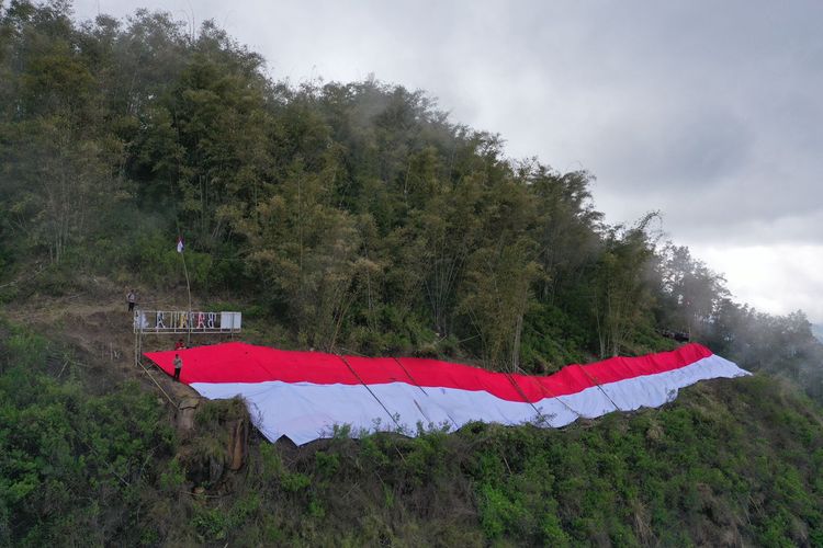 Foto : Personil Polres Ngada bersama anggota pramuka Kabupaten Ngada dan para warga masyarakat  mengibarkan  Bendera Merah Putih raksasa sepanjang 200 meter, bertempat di bukit Wolo Ngadha, Kecamatan Bajawa Kabupaten Ngada, Selasa( 16/08/2022).