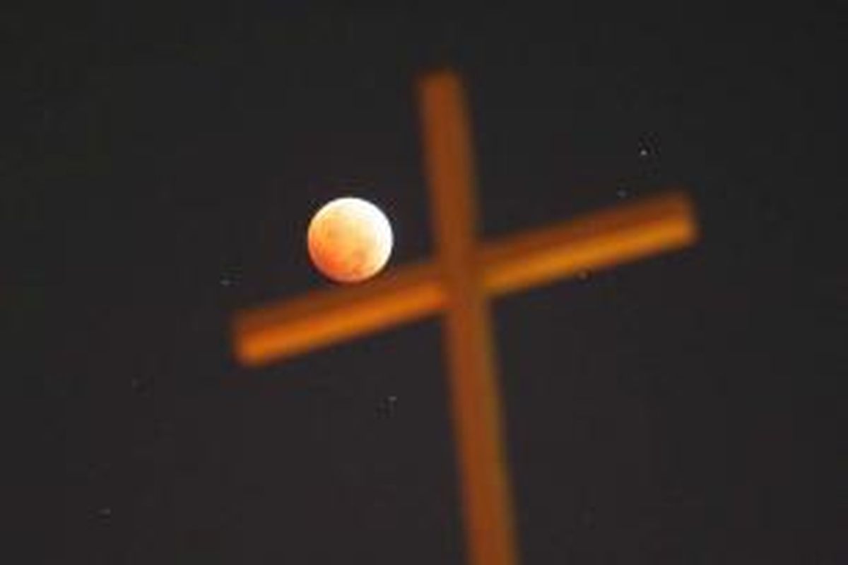 Gerhana bulan dengan latar depan salib di Los Angeles, California, 8 Oktober 2014. Warna merah pada gerhana bulan dipengaruhi oleh pembiasan atmosfer Bumi, disebut dengan 'bulan merah darah'.