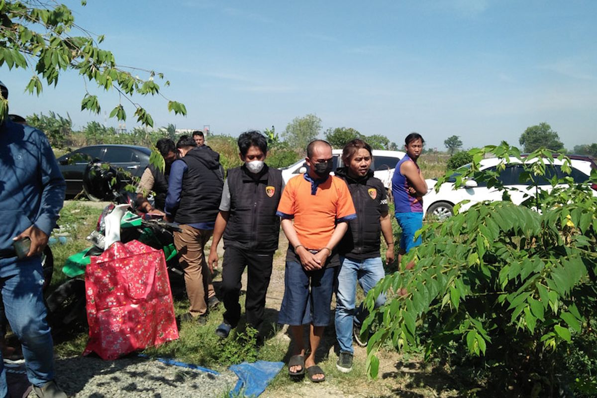 Tersangka dalam perkara temuan mayat wanita terbungkus tas plastik beberapa waktu lalu, HS (tengah) saat dibawa petugas kepolisian untuk melakukan reka adegan, Rabu (28/9/2022).