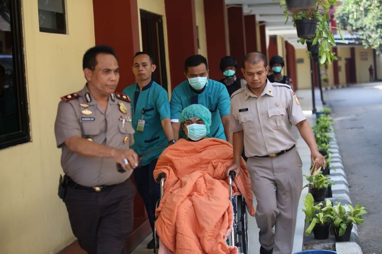 Seorang pasien ditutupi selimut oranye dan masker hijau tiba di RS Polri, Jakarta Timur, Kamis (10/5/2018). Ia tampak dikawal petugas bersenjata. 