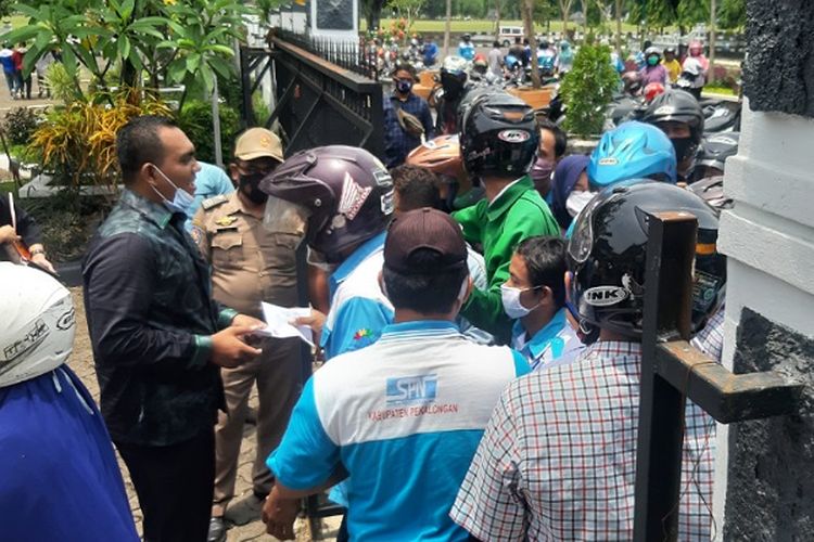 Anggota DPRD Kabupaten Pekalongan Jawa Tengah candra Saputra membagikan uang kepada buruh yang sesang berunjuk rasa di halaman DPRD Kab. Pekalongan.