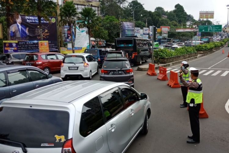 Petugas kepolisian sedang mengatur arus lalu lintas di Simpang Gadog, Puncak, Bogor, Jawa Barat, Sabtu (14/4/2018). 
