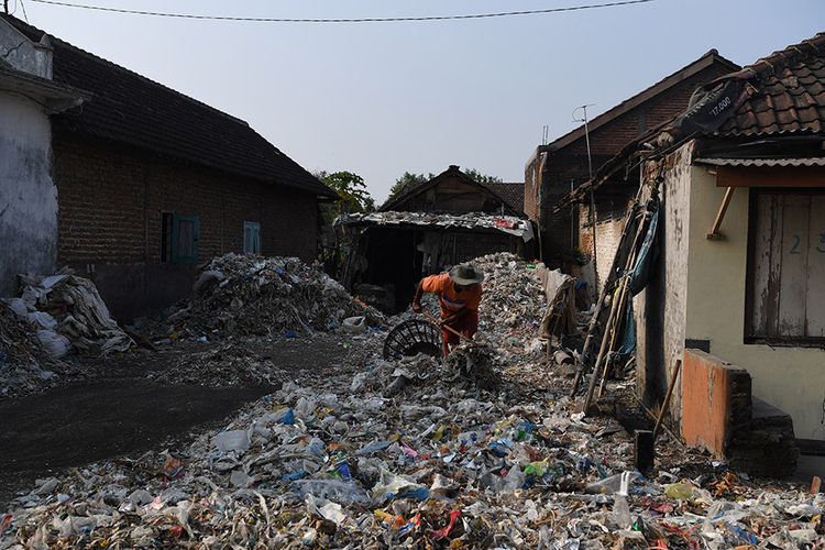 Warga memilah tumpukan sampah plastik impor di halaman rumahnya di Desa Bangun di Mojokerto, Jawa Timur, Rabu (19/6/2019). Berdasarkan data Lembaga Kajian Ekologi dan Konservasi Lahan Basah Ecoton, masuknya sampah dengan merk dan lokasi jual di luar Indonesia, diduga akibat kebijakan China menghentikan impor sampah plastik dari sejumlah negara di Uni Eropa dan Amerika yang mengakibatkan sampah plastik beralih tujuan ke negara-negara di ASEAN.