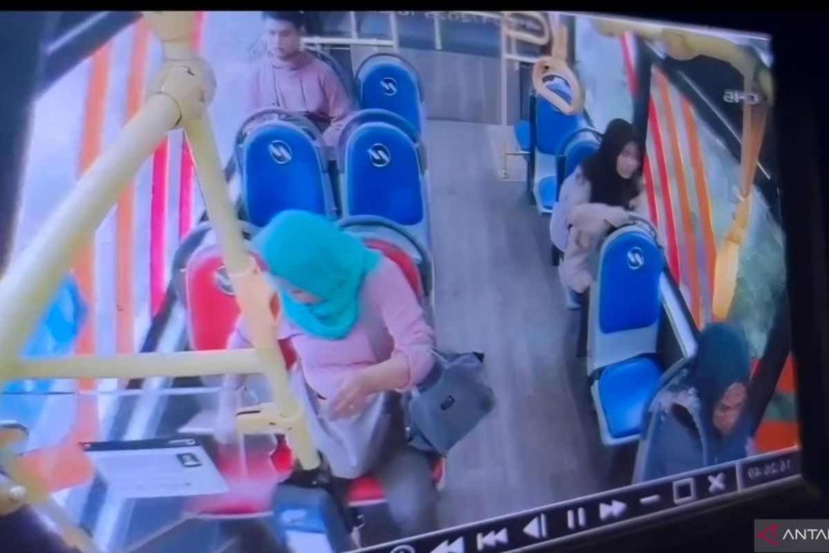 Tangkapan layar dari rekaman CCTV yang memperlihatkan pelaku pencurian berinisial M (memakai penutup kepala berwarna hijau) saat mencuri laptop yang tertinggal di Bus Transjakarta, Jakarta, Kamis (15/5/2025).