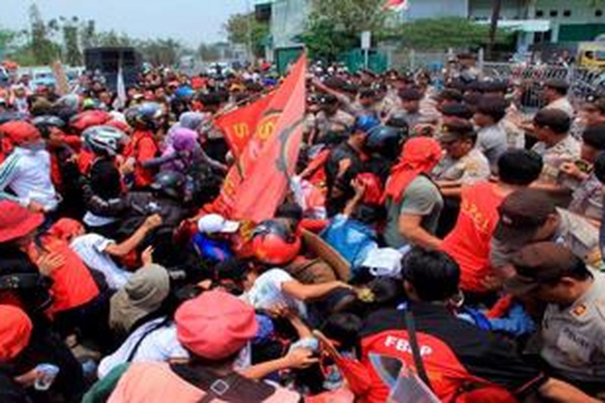 Sejumlah buruh terjatuh saat berusaha masuk menembus barisan polisi di Kawasan Berikat Nusantara Cakung, Jakarta Utara, Rabu (3/10/2012). Para buruh menuntut penghapusan sistem kerja alihdaya, upah layak, dan perbaikan kesejahteraan.  