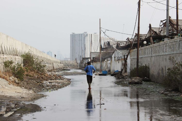 Warga beraktivitas di jalan tergenang rob (air pasang laut) di sekitar tanggul laut, Muara Baru, Jakarta Utara, Sabtu (12/10/2019). Pemerintah Provinsi DKI Jakarta dan Kementerian Pekerjaan Umum dan Perumahan Rakyat (PUPR) mengambil alih pembangunan segmen tanggul laut National Capital Integrated Coastal Development ( NCICD) di utara Jakarta.