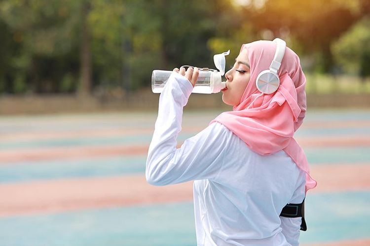 Ilustrasi perempuan muslim mengonsumsi air putih saat berolahraga. 