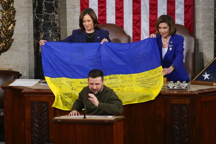 Wakil Presiden Kamala Harris, kiri, dan Ketua DPR Nancy Pelosi dari California, kanan, diberikan bendera Ukraina yang ditandatangani oleh pasukan garis depan di Bakhmut, di provinsi Donetsk yang diperebutkan Ukraina, yang disampaikan oleh Presiden Ukraina Volodymyr Zelenskyy kepada anggota parlemen saat berpidato di depan rapat gabungan Kongres di Capitol Hill di Washington, Rabu, 21 Desember 2022.