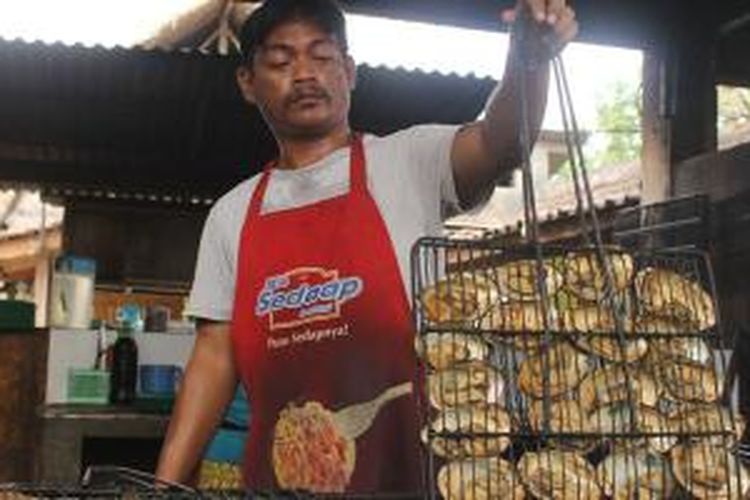 Seorang pekerja warung yang bertugas di dapur Warung Pondok Bambu, Kabupaten Jembrana, Bali, memperlihatkan hasil olahannya yang segar.