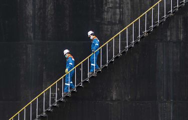 Pekerja PT Pertamina Hulu Rokan menaiki anak tangga tangki pengumpul produksi minyak (Tank Farm) di Blok Rokan, Dumai, Riau.